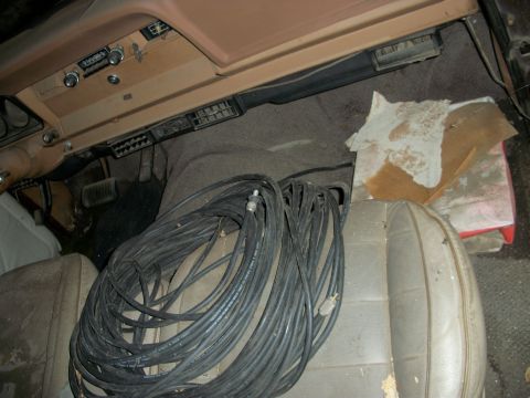 1976 Jeep J-10 - A large bundle of black cables is coiled on the passenger seat of this dusty vehicle's interior.