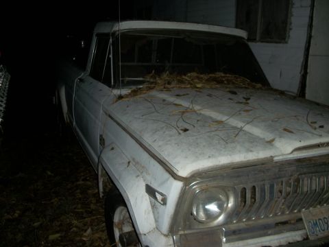 1976 Jeep J-10 - This 1976 Jeep J-10 pickup truck is seen from the front quarter angle, covered in debris.