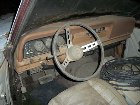 1976 Jeep J-10 - The dusty interior of a classic vehicle, a worn steering wheel and dashboard.