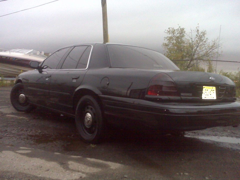 Black 2005 Ford Crown Victoria parked on wet ground, rear quarter view