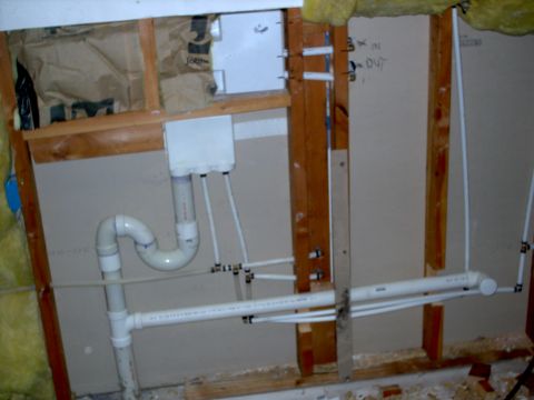 1965 Ford Mustang - A view of unfinished wall construction showing various plumbing pipes and fittings.