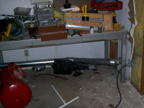 1965 Ford Mustang - A cluttered workbench and floor with various tools and mechanical parts.
