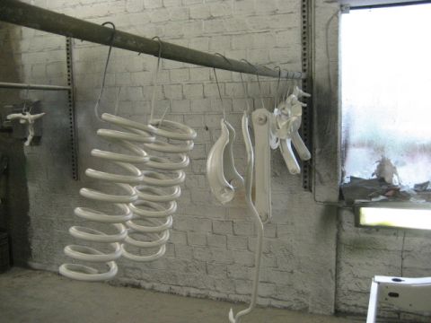 1973 Ford Ranchero - Automotive suspension components are painted and hung to dry in a workshop environment.