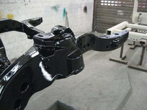 1973 Ford Ranchero - A freshly painted black vehicle frame is visible in a workshop setting, with another frame in the background.