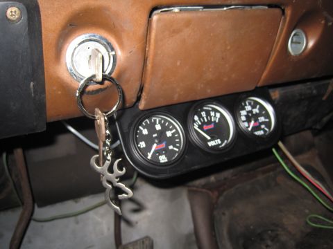 1979 Ford Bronco - Interior view of a vehicle's dashboard an oil pressure gauge, voltmeter, and water temperature gauge, with keys in the ignition.
