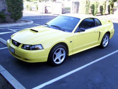 2002 Ford Mustang - A yellow 2002 Ford Mustang is parked in a lot, showing its front 3/4 view.