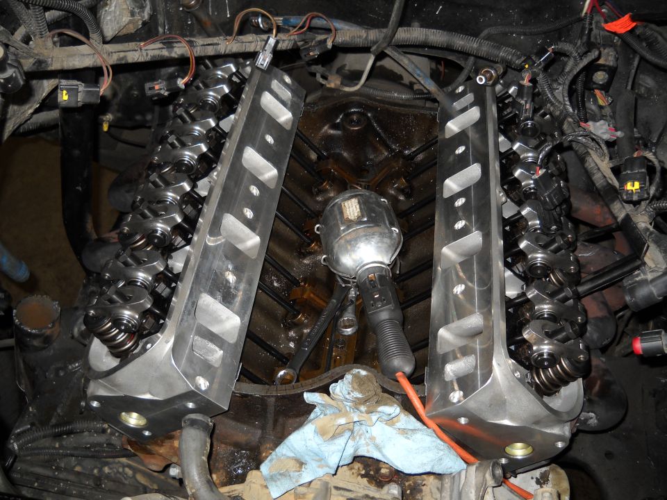 V8 engine with intake removed showing aluminum heads, valvetrain, work light and wrench in the lifter valley