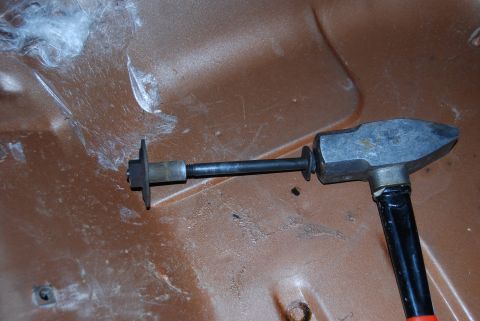 1982 Ford Bronco - A dent puller tool is positioned on a brown metal surface, possibly inside a vehicle's body panel.
