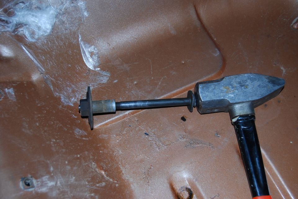 Dent puller tool with black handle and metal head on brown surface with white debris