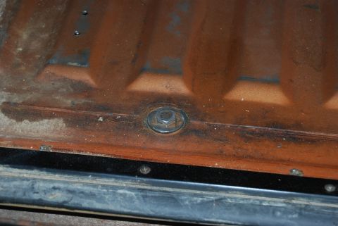 1982 Ford Bronco - Close-up of a rusted metal panel with a bolt, likely from a vehicle's undercarriage or interior.
