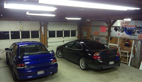 2002 Chrysler 300M - Two sedans, a black Chrysler and a blue Mitsubishi, are parked inside a garage.