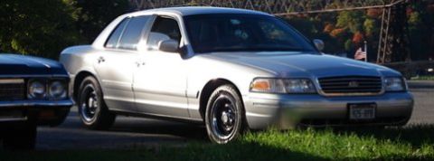 2000 Ford Crown Victoria - A silver sedan is parked on the grass with another vehicle to its left.