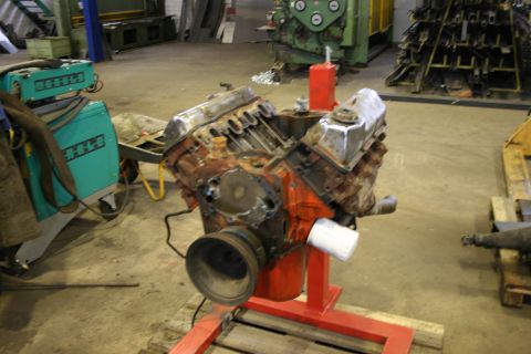 1973 Ford Ranchero - A V8 engine is mounted on a stand in a garage, with a welding machine nearby.