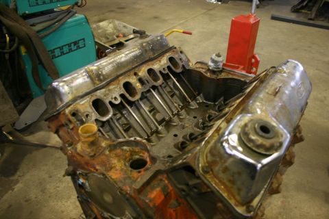 1973 Ford Ranchero - A V8 engine block sits on a shop floor, showing signs of rust and wear.
