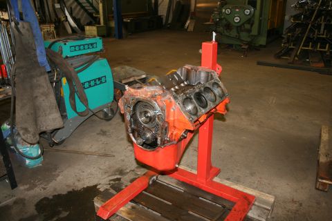 1973 Ford Ranchero - V8 engine block on a stand in a workshop setting, next to welding equipment.