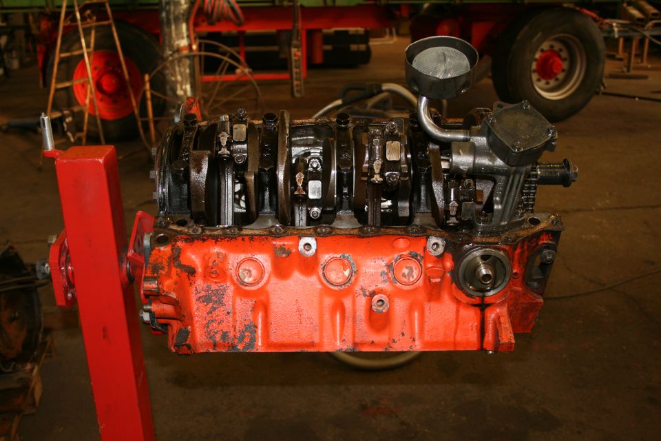 Ford V8 engine block with crankshaft visible, mounted on red engine stand
