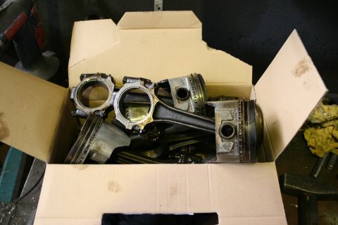 1973 Ford Ranchero - Several engine pistons with connecting rods are piled inside a cardboard box.