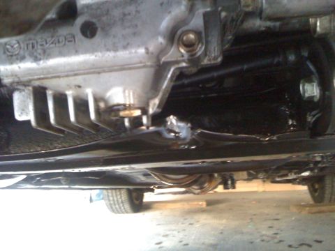1994 Ford Probe - The underside of a vehicle reveals a transmission with Mazda branding and visible suspension parts.