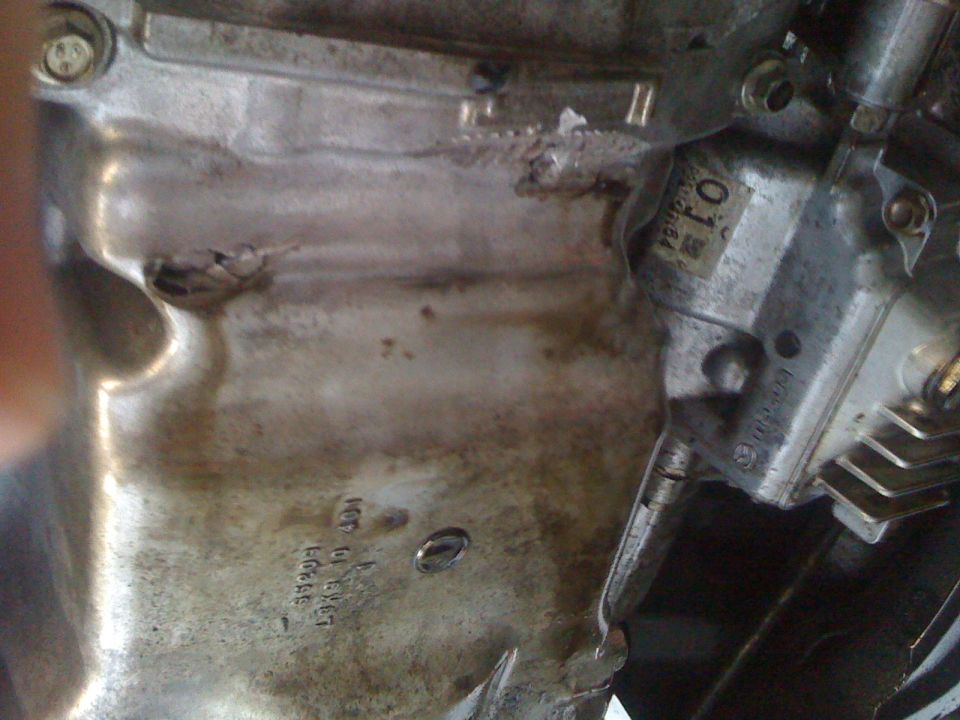 Engine oil pan with visible text and a small hole