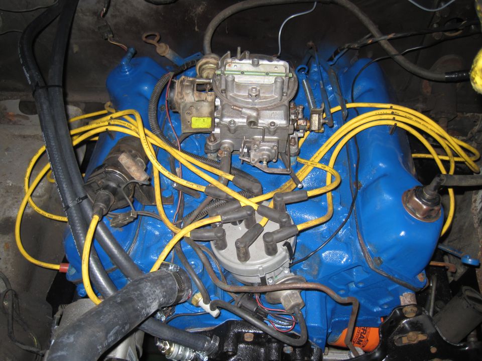 Close-up of a blue engine with yellow spark plug wires and a carburetor