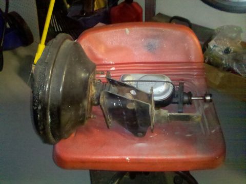 1978 Ford Bronco - A brake booster and master cylinder assembly is shown on a red plastic seat.