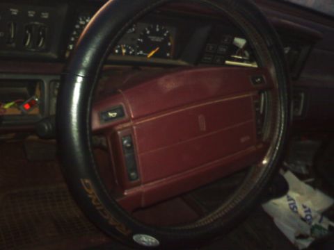 1990 Ford Bronco - The interior of a car features a red dashboard and steering wheel, with visible gauges.