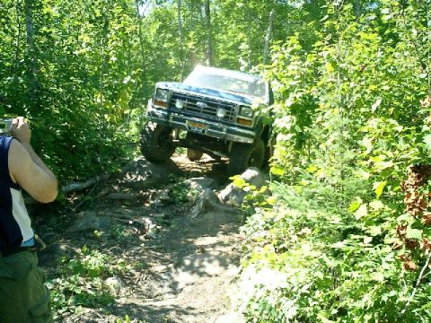 1986 Ford Bronco - This 1986 Ford Bronco is shown tackling a challenging off-road course through dense woods.