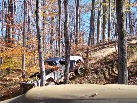 1987 Ford F-250 - An off-road vehicle is on a challenging trail surrounded by trees with fall foliage.