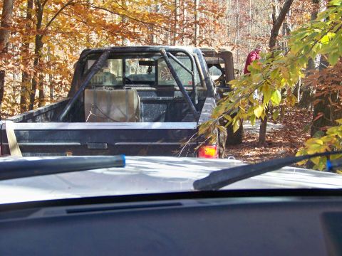 1987 Ford F-250 - A modified pickup truck is parked in a forest during autumn, with another vehicle behind it.