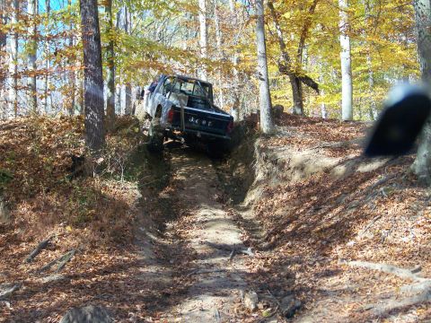 1987 Ford F-250 - A Jeep truck navigates a challenging off-road trail during an autumn excursion.