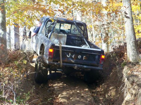 1987 Ford F-250 - This Jeep pickup truck, equipped with a roll cage, tackles a challenging off-road course during a wheeling trip.