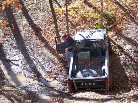 1987 Ford F-250 - Jeep pickup truck with roll cage stuck in mud, driver checking door.
