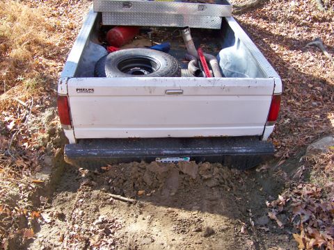 1987 Ford F-250 - A white pickup truck is stuck in the mud, with its rear end partially buried.