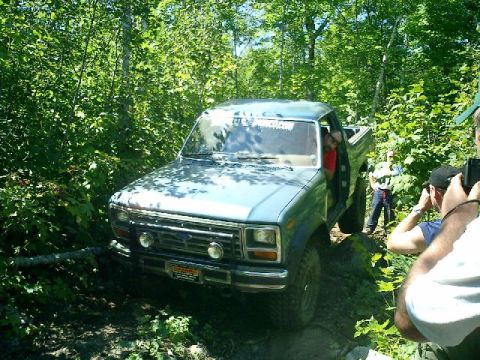 1986 Ford Bronco - This 1986 Ford Bronco is navigating a wooded trail with onlookers present.