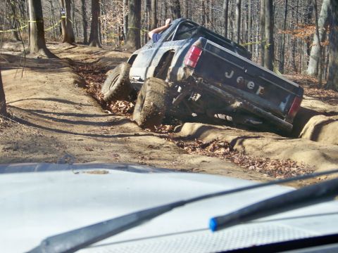 1987 Ford F-250 - Off-road Jeep pickup truck navigating a difficult trail in a wooded area.