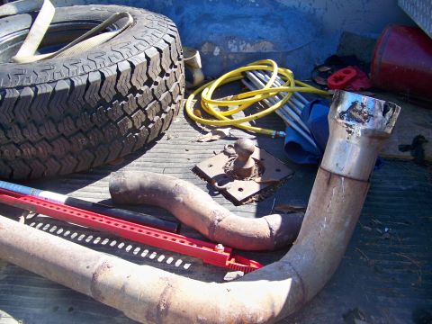1987 Ford F-250 - Spare tire and exhaust parts are stored in the bed of a pickup truck.