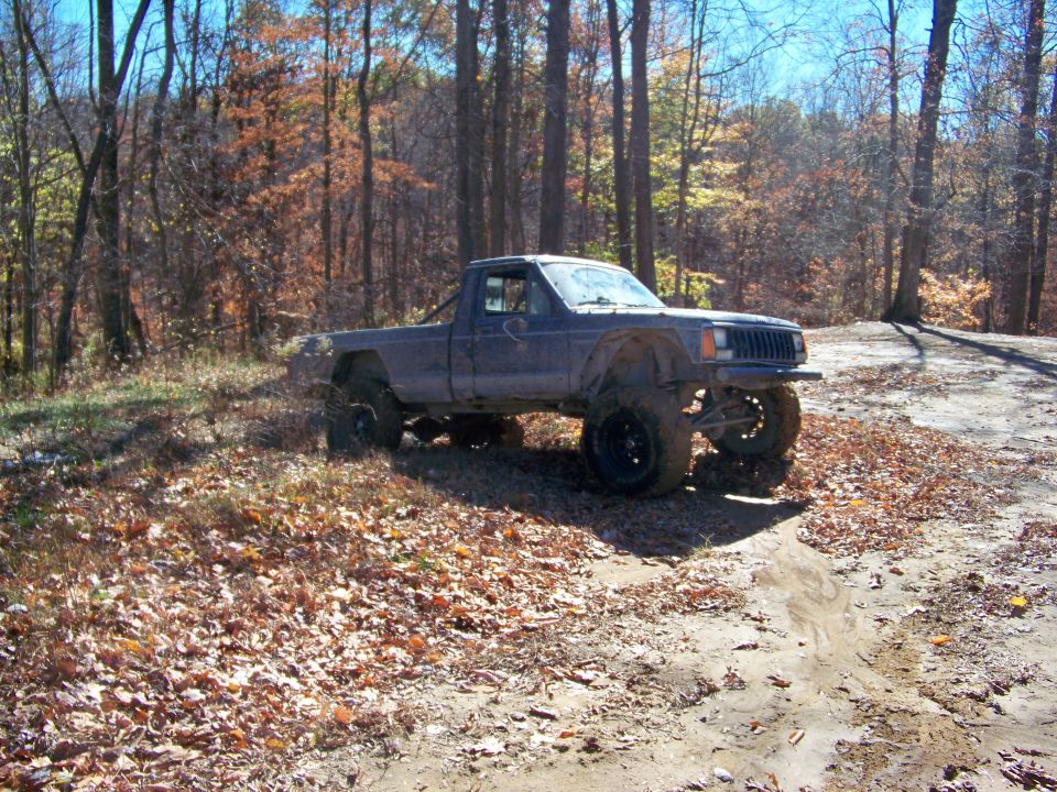 Modified Jeep Comanche pickup truck on a dirt path in the woods
