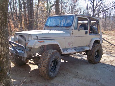 1987 Ford F-250 - This tan Jeep Wrangler, likely from the late 1980s or early 1990s, is equipped for off-road use with a brush guard and oversized tires.