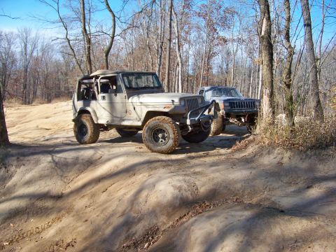 1987 Ford F-250 - Two off-road vehicles navigate a wooded trail during an outing.