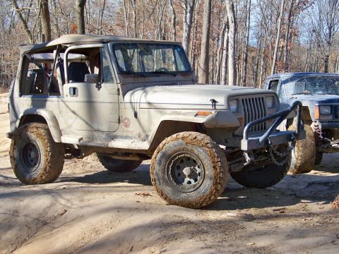 1987 Ford F-250 - Two off-road vehicles are parked on a dirt path surrounded by trees in a wooded area.