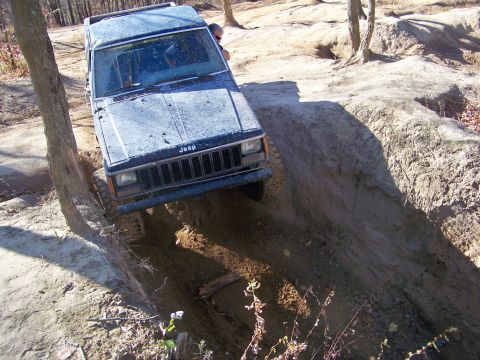 1987 Ford F-250 - A Jeep Cherokee navigates a steep dirt incline during an off-road excursion.