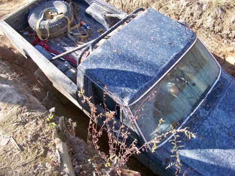1987 Ford F-250 - This 1987 Ford F-250 is stuck in a muddy ditch, with a spare tire and recovery gear in the bed.