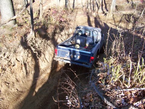 1987 Ford F-250 - Jeep pickup truck navigates a tight trail through a wooded area.