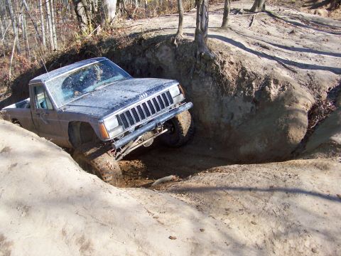 1987 Ford F-250 - This Jeep Comanche pickup truck is navigating a challenging off-road obstacle.