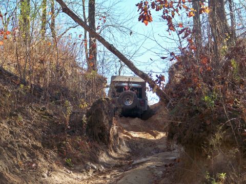1987 Ford F-250 - A Jeep navigates a challenging off-road trail during daylight hours.