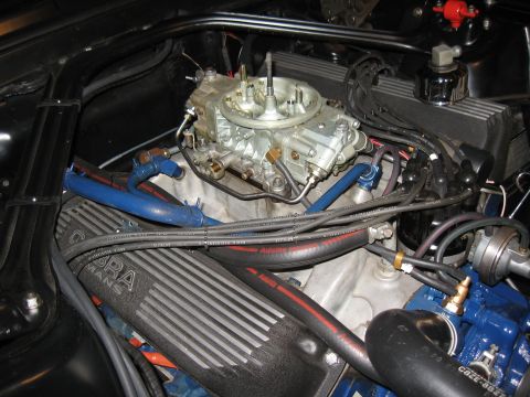 1968 Shelby GT500 - Close-up of a car engine bay Cobra Manifold valve covers and a Holley carburetor, with various hoses and wiring visible.