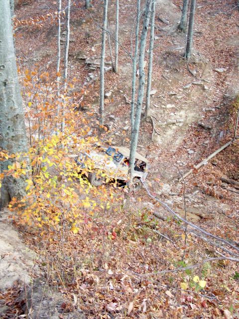 1987 Ford F-250 - A vehicle navigates a challenging off-road trail through a forest during autumn.