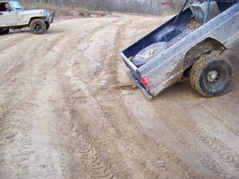 1987 Ford F-250 - Two off-road vehicles navigate a muddy track during a wheeling trip.