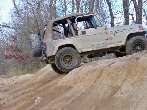 1987 Ford F-250 - A tan Jeep Wrangler navigates a steep, rocky trail during an off-road excursion.