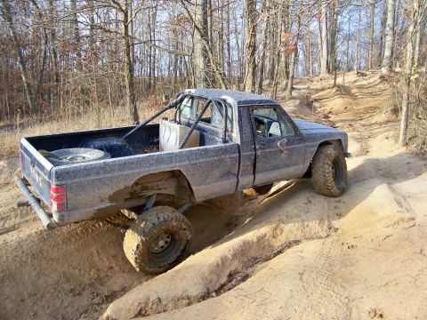 1987 Ford F-250 - This heavily modified pickup truck navigates a challenging off-road course with its large tires and protective roll cage.